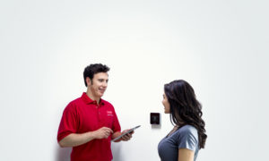 A technician showing a woman a smart thermostat
