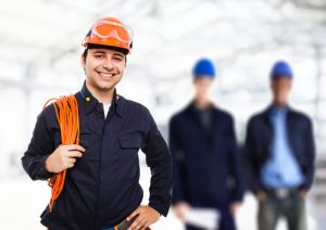 Electrician smiling with two other people blurred in the background