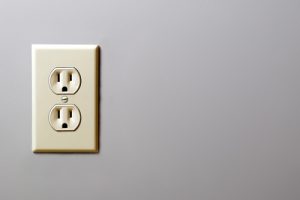 A white outlet port on a gray wall