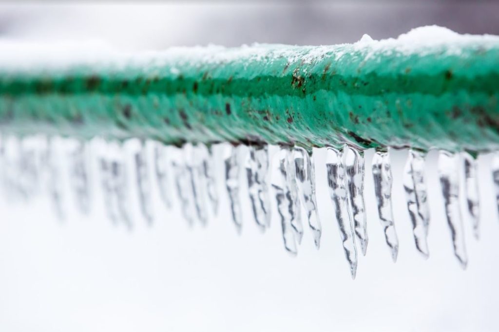 Close up of green pipes frozen over