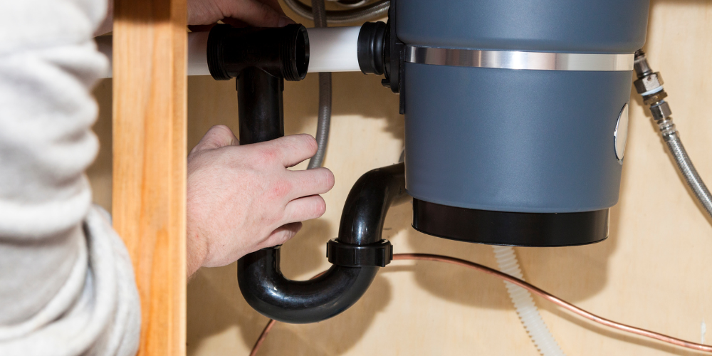 Plumber inspecting and repairing sink pipe - Garbage Disposals 101: What Every Homeowner Should Know
